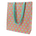 Pink shopping bag with floral block-print pattern and carry handles.