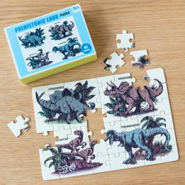 Small jigsaw puzzle with prints of dinosaurs being put together on table