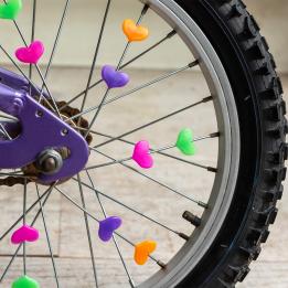 Colourful spoke hearts attached to a bicycle wheel, representing cycling-themed gifts.