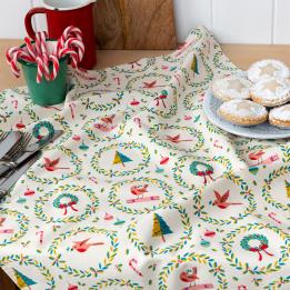 Cotton tea towel with a festive holiday design featuring Christmas trees, wreaths