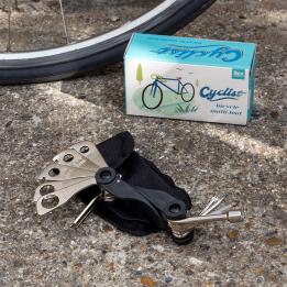 Cyclist multi-tool set with various attachments placed beside a bicycle wheel and a box