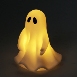 White ghost night light with black eyes, with its light turned on