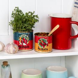 Two passata tins repurposed as herb and spice holders on a rustic kitchen shelf.