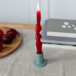 grey ceramic candle holder with a cylindrical shape and wide flat base, holding a lit red candle