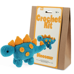 Blue crocheted dinosaur placed next to its packaging