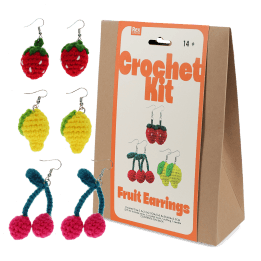 Crochet kit packaging placed beside three finished crocheted earrings shaped like strawberries, lemons, and cherries