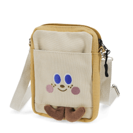 Beige and yellow crossbody bag with a front pocket featuring a smiling face design and two small brown plush feet at the bottom.