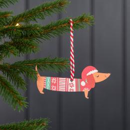 Wooden Christmas decoration of sausage dog wearing festive jumper and hat hanging on tree