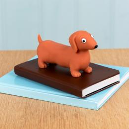 Squeezy squishy toy shaped like a brown sausage dog with floppy ears and a cute face placed on the book.