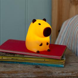 Yellow capybara night light with dark brown ears, nose and feet shown with light on