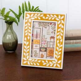 picture frame with a mustard yellow border and white leaf patterns