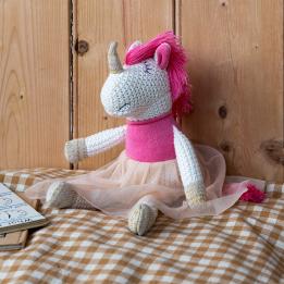 Knitted unicorn toy wearing a pink top and skirt