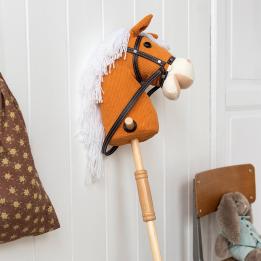 hobby horse toy with white mane and black bridle on a wooden stick