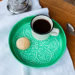 enamel trinket dish in green displayed with a cup of coffee and biscuit.