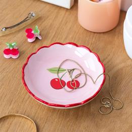 round ceramic trinket dish with scalloped red edge and cherry design in the center