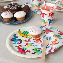 Dinosaur-themed party plate displayes with matching napkins and a cup.