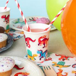 Dinosaur‑themed party paper cup with matching paper plate and napkins beside it.