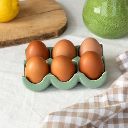 Green ceramic egg holder displayed with six eggs. 
