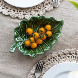 Green ceramic leaf-shaped trinket dish displayes with yellow tomatoes