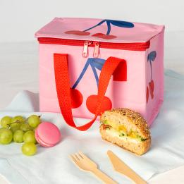 A cherry‑themed insulated lunch bag placed on a table next to fruit.