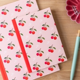 Pink notebook with cherry design on the cover.