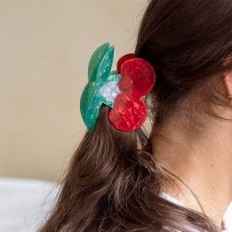 Hair claw clip featuring a sweet cherry design in red, green and white, with hints of marbling and translucence. 