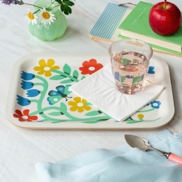 Wooden tray with colourful floral and butterfly design, shown with a glass and folded napkin.