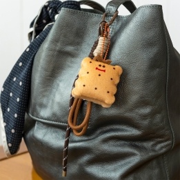 Plush toast bag charm with brown cord strap and metal clip attachment