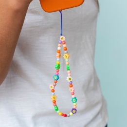 olourful beaded phone strap with smiley flower charms shown attached to an orange phone.