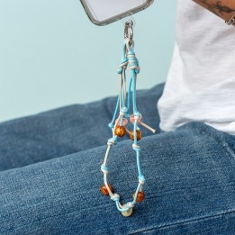 Blue and tan cord phone strap with decorative beads shown hanging from a phone