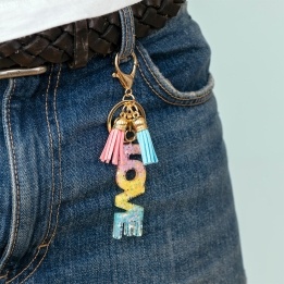 Gold keyring with colourful “LOVE” letter charm and pink and blue tassels.