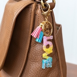 Gold keyring with colourful “LOVE” letter charm and pink and blue tassels.
