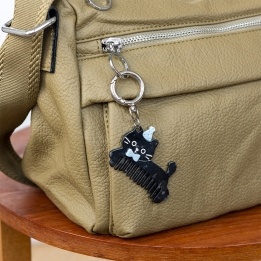 Black cat-shaped keyring with comb teeth, blue bow and hat attached to a silver ring.