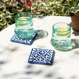 Blue ceramic tile coasters with white pattern shown beside two glasses of lemon water.