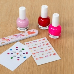 Unicorn nail kit contents including three nail polishes, a unicorn nail file, and unicorn-themed nail stickers.
