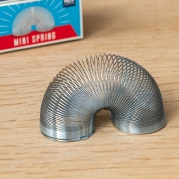 Mini metal spring toy displayed in a curved shape beside blue Wild Bear branded retail packaging.