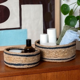 Set of two round woven storage baskets with black stripe detail.
