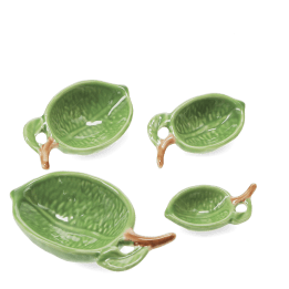 Set of four ceramic measuring spoons shaped like green leaves with brown stem handles 