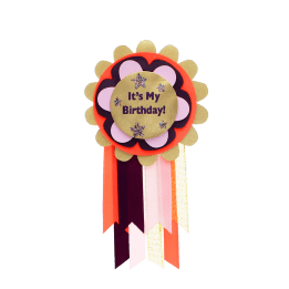Colourful birthday badge with a gold centre reading ‘It’s My Birthday!’ and ribbons.