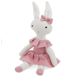 Knitted rabbit toy with long ears, wearing a pink dress with a ruffled collar and a matching bow on one ear