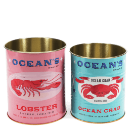 Two Ocean’s Brand storage tins featuring lobster and crab illustrations in pink and blue.
