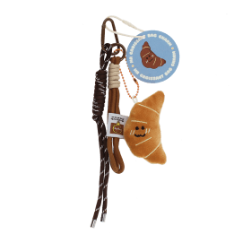 Plush croissant bag charm with brown cord strap and metal clip attachment with tag.