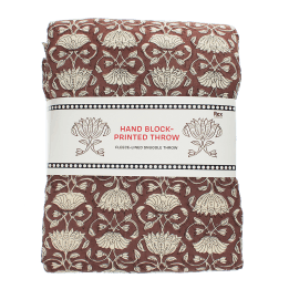 Brown hand block-printed throw with floral pattern, folded in packaging.