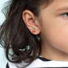 Stick-on earrings in cherry and lightning bolt shapes on a kid’s ear