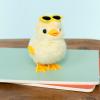 A fluffy yellow wind-up duck toy wearing yellow sunglasses