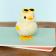 A fluffy yellow wind-up duck toy wearing yellow sunglasses