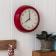 Round red wall clock with black hands and numbers,