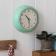 Round mint green wall clock with black hands and numbers