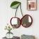 Wall mirror shaped like two cherries with red frames and green leaf detail hanging on the wall.
