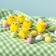 Six small fluffy yellow chicks arranged among coloured eggs.